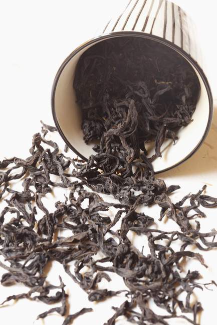 Folhas de chá derramando fora de uma xícara — Fotografia de Stock