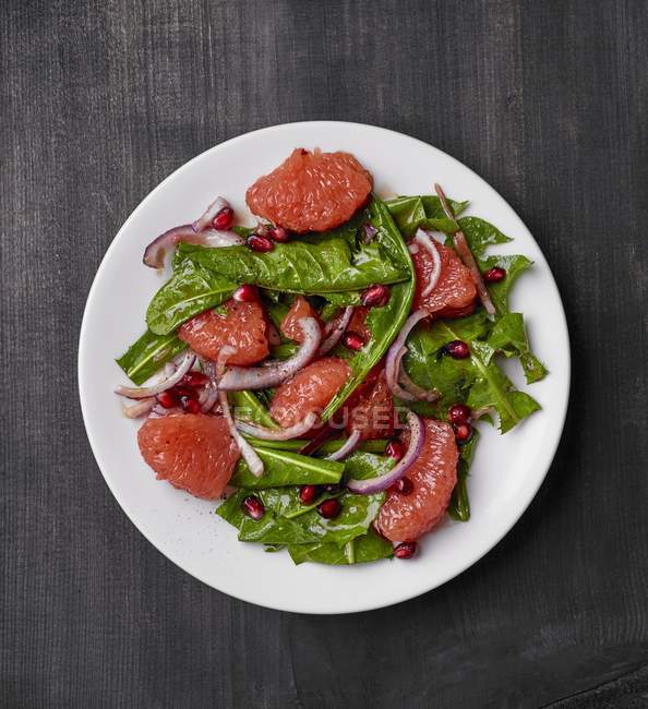 Салат из одуванчиков с семенами грейпфрута и граната — стоковое фото
