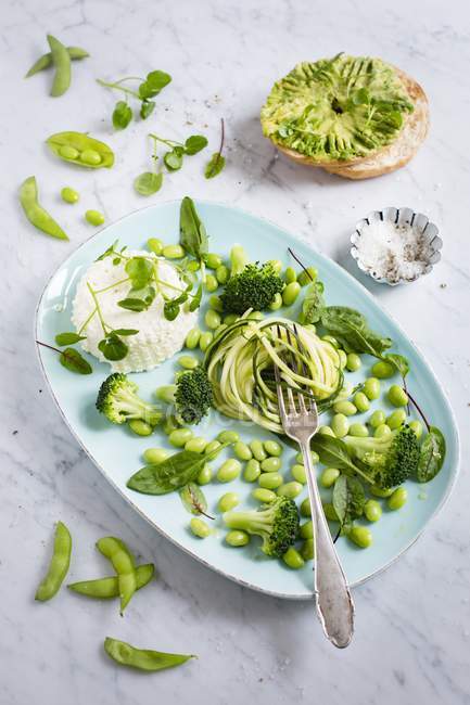 Green salad on platter with avocado bagel — Stock Photo