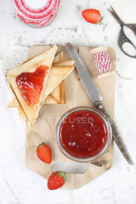 Vista dall'alto di marmellata di fragole fatta in casa in un vaso e su triangoli di pane tostato — Foto stock