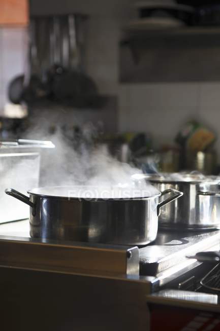 Uma panela de água quente em um fogão dentro de casa — Fotografia de Stock