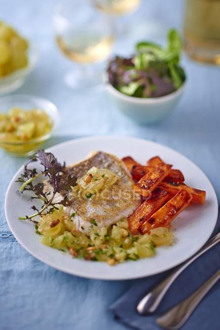 Hake with sweet potato chips on white plate — Stock Photo