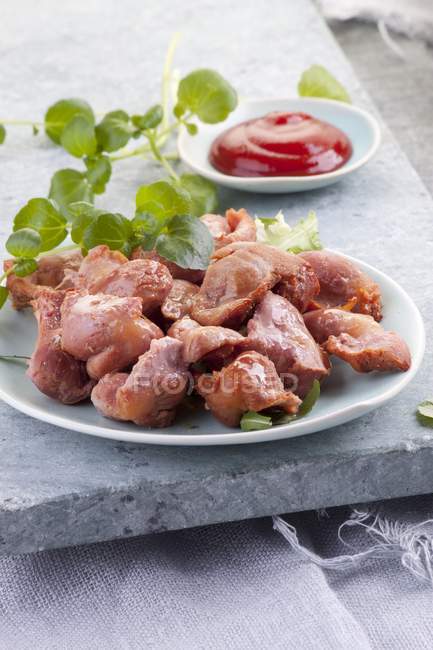 Крупный план маринованных куриных желудков с травами и соусом — стоковое фото