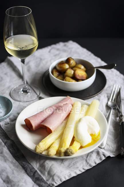 Closeup view of asparagus with ham, poached egg and white wine — Stock Photo