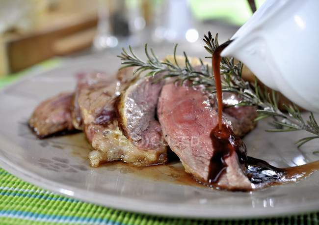 Sliced Grilled lamb with gravy and rosemary — Stock Photo