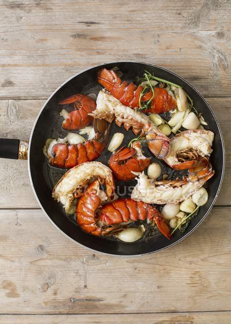 Fried lobster tails with garlic in a pan  over wooden surface — Stock Photo