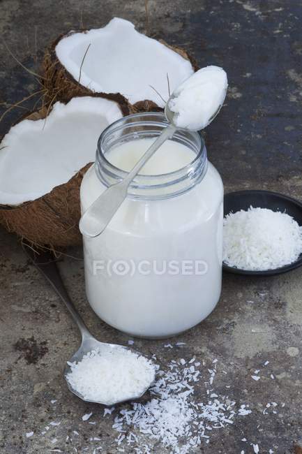 Elevated view of coconut oil with coconut flakes and fresh broken coconut — Stock Photo