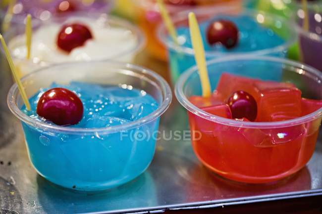 Vista close-up de geléias coloridas com cerejas em tigelas de plástico — Fotografia de Stock