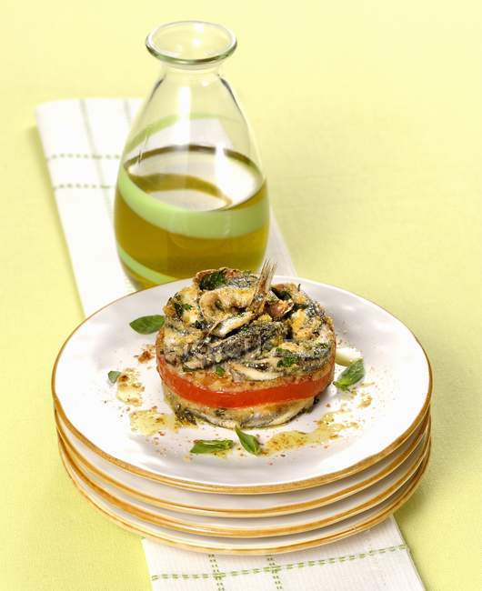 Tortino di alici - tartaleta de anchoa sobre platos apilados sobre toalla sobre superficie verde - foto de stock