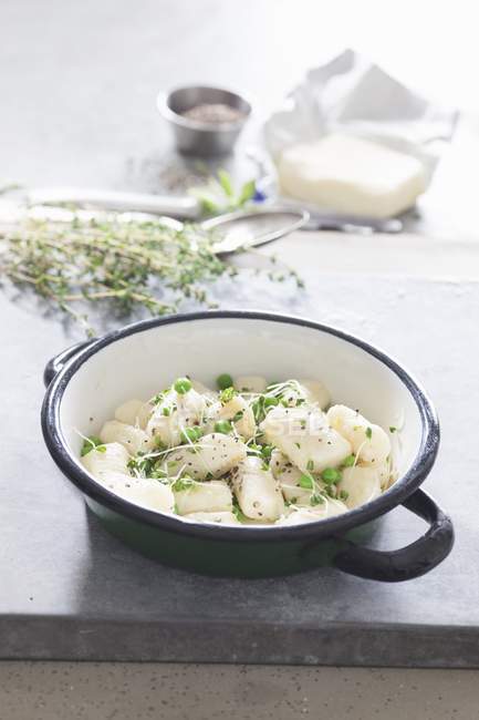 Gnocchi with peas in bowl over marble grey surface — Stock Photo