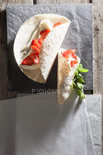Vista de cerca de las envolturas de Tortilla con crema de vainilla y fresas - foto de stock