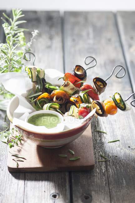 Kebabs de légumes avec sauce à la menthe dans un bol sur une surface en bois — Photo de stock