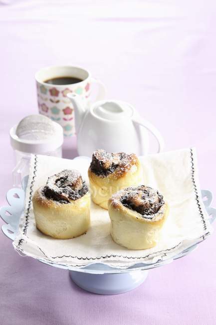 Plum and chocolate buns over towel on cake stand — Stock Photo