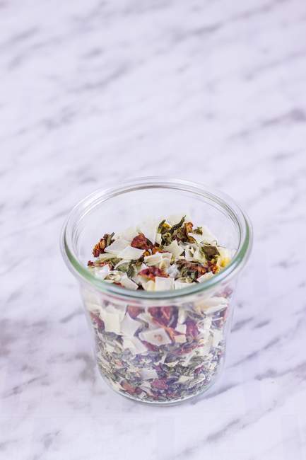 Una miscela vegetale liofilizzata in un bicchiere su una superficie di marmo viola — Foto stock
