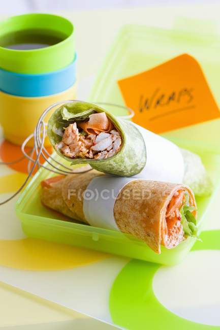 Green and red tandoori chicken wraps over colored surface of table — Stock Photo