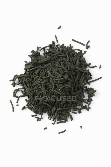 Closeup top view of dry Spirulina on a white surface — Stock Photo