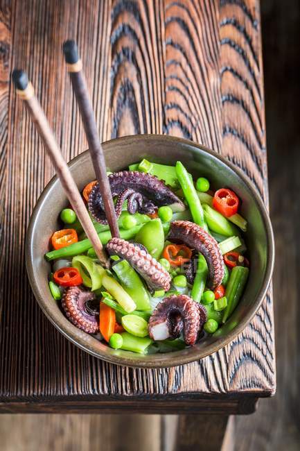 Vegetables with noodles and octopus on wooden table — Stock Photo
