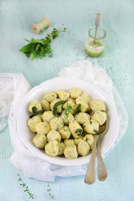 Elevated view of herb Gnocchi in a bowl with a spoon — Stock Photo
