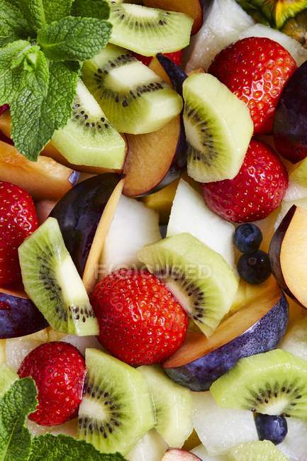 Ensalada de frutas con hojas de menta y bayas - foto de stock