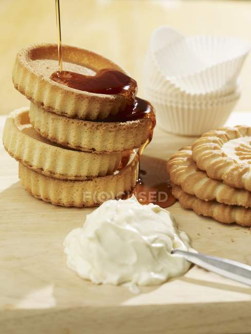 Closeup view of pouring syrup over piled tartlet bases — Stock Photo