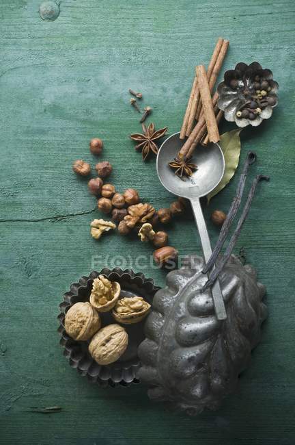 Vue de dessus des épices carieuses et des noix dans des boîtes de cuisson sur une surface en bois rustique — Photo de stock