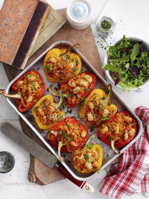 Roasted stuffed peppers in baking dish over wooden desk — Stock Photo