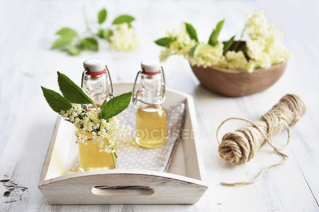 Vista close-up de xarope de sabugueiro caseiro com flores de sabugueiro frescas — Fotografia de Stock