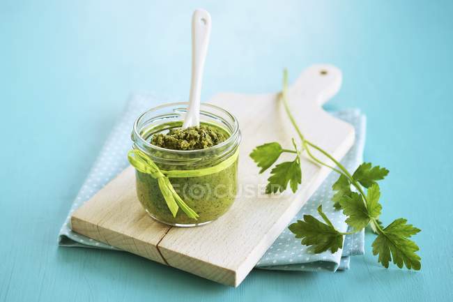 Closeup view of a jar of parsley Pesto on a wooden board — Stock Photo