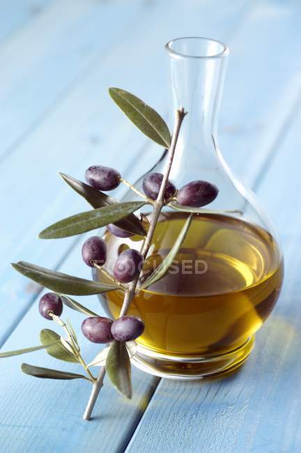 Jarra de aceite de oliva y ramita de aceitunas - foto de stock