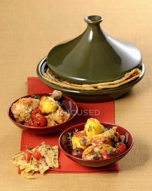 Closeup view of braised chicken with potatoes, tomatoes and flat bread — Stock Photo