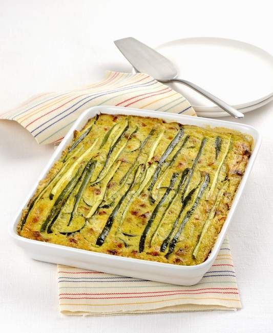 Courgette bake in white dish over towel — Stock Photo