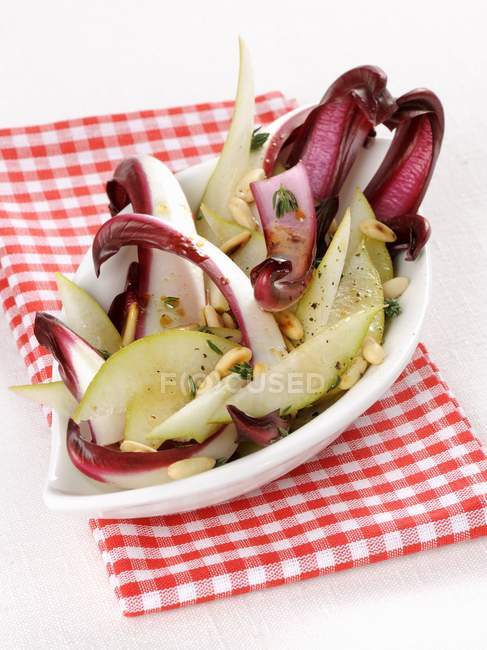 Radicchio con peras y piñones en plato blanco sobre toalla - foto de stock