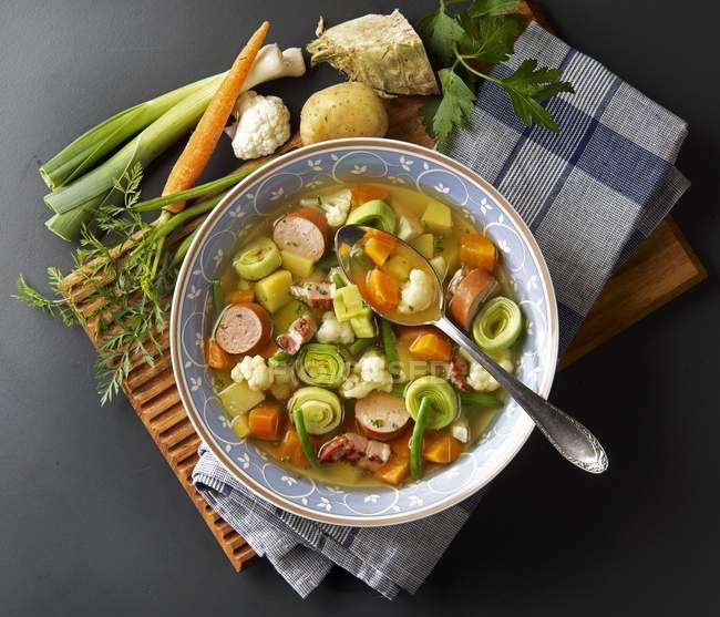 Vegetable stew with sausage and bacon  on white plate with spoon — Stock Photo