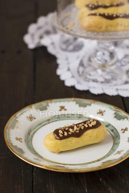 Chocolate eclairs with chopped nuts — Stock Photo