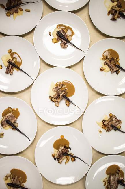 Assiettes de plat principal soigneusement composées pour un dîner-bénéfice pop-up avec des produits de saison — Photo de stock
