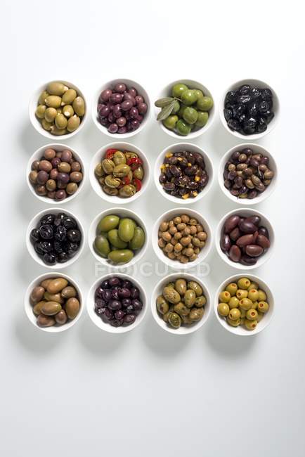 Разноцветные оливки в белых чашах — стоковое фото