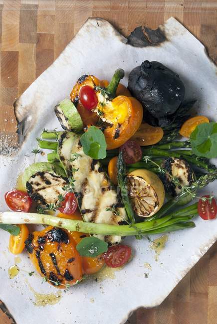 Mixed grilled vegetables on a piece of paper over wooden surface — Stock Photo