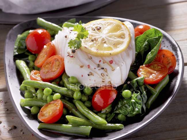Cod fillet on bed of vegetables — Stock Photo