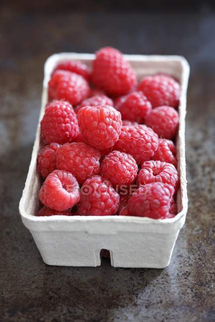 Fresh raspberries in paper punnet — Stock Photo