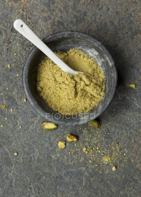 Вид зверху на мелені фісташкові горіхи в кам'яній мисці — стокове фото