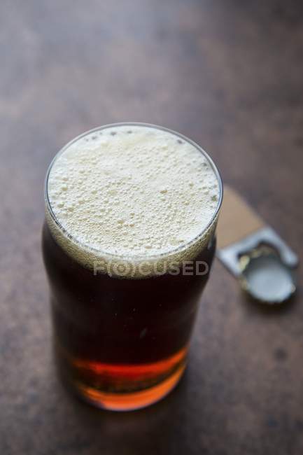 Bicchiere di birra ambrata con apribottiglie — Foto stock