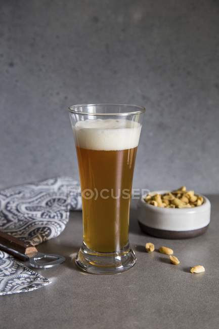 Wheat beer in glass and peanuts — Stock Photo