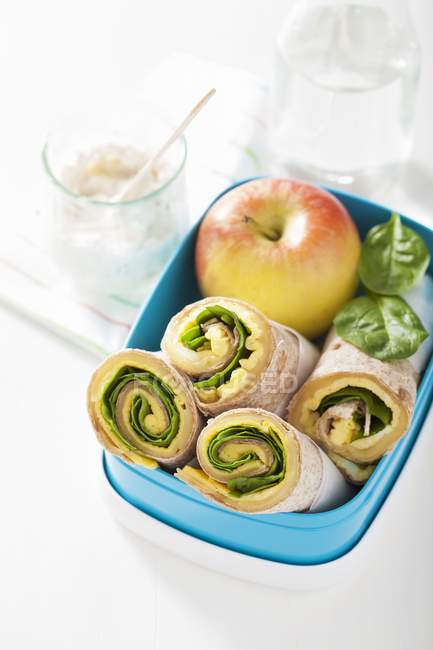 Breakfast burritos in a lunch box over white surface — Stock Photo