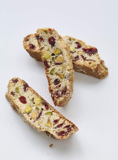 Vue rapprochée de Biscotti italien avec raisins secs et pistaches sur la surface blanche — Photo de stock