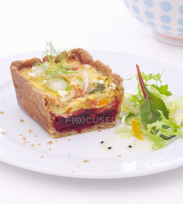 Beetroot and fennel quiche with lettuce on white plate — Stock Photo
