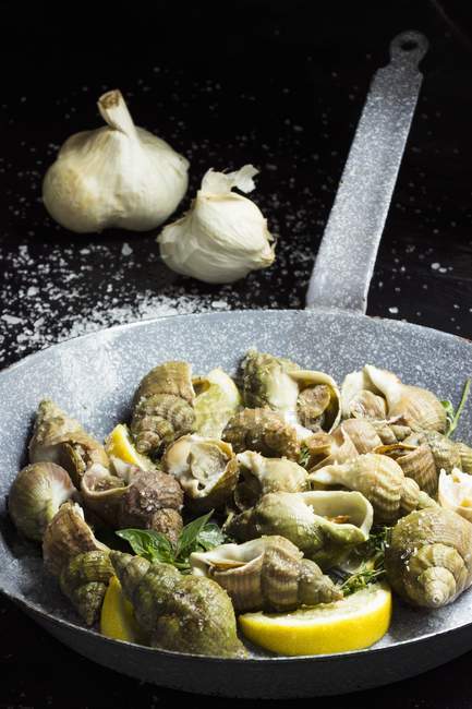 Closeup view of fried whelks and garlic — Stock Photo