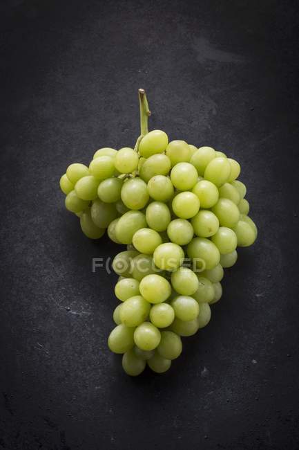 Uvas verdes em uma superfície preta — Fotografia de Stock