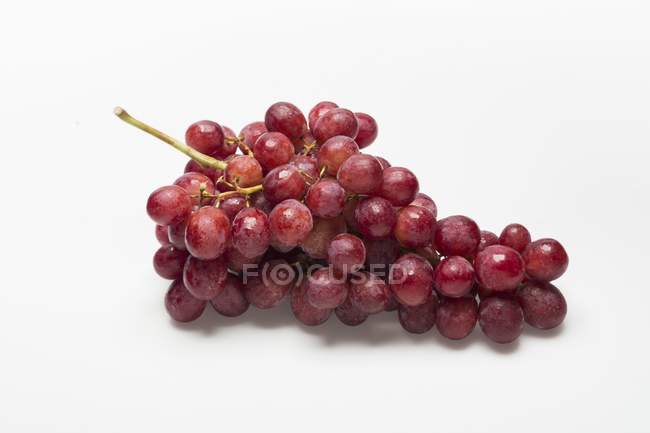 Uvas vermelhas em uma superfície branca — Fotografia de Stock