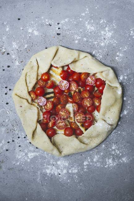 Tarta de tomate sin cocer con jamón sobre superficie gris - foto de stock