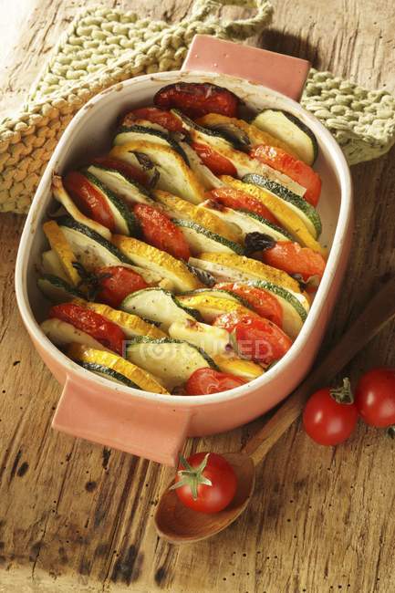 Zucchini und Tomaten in Auflaufform über Holzoberfläche backen — Stockfoto